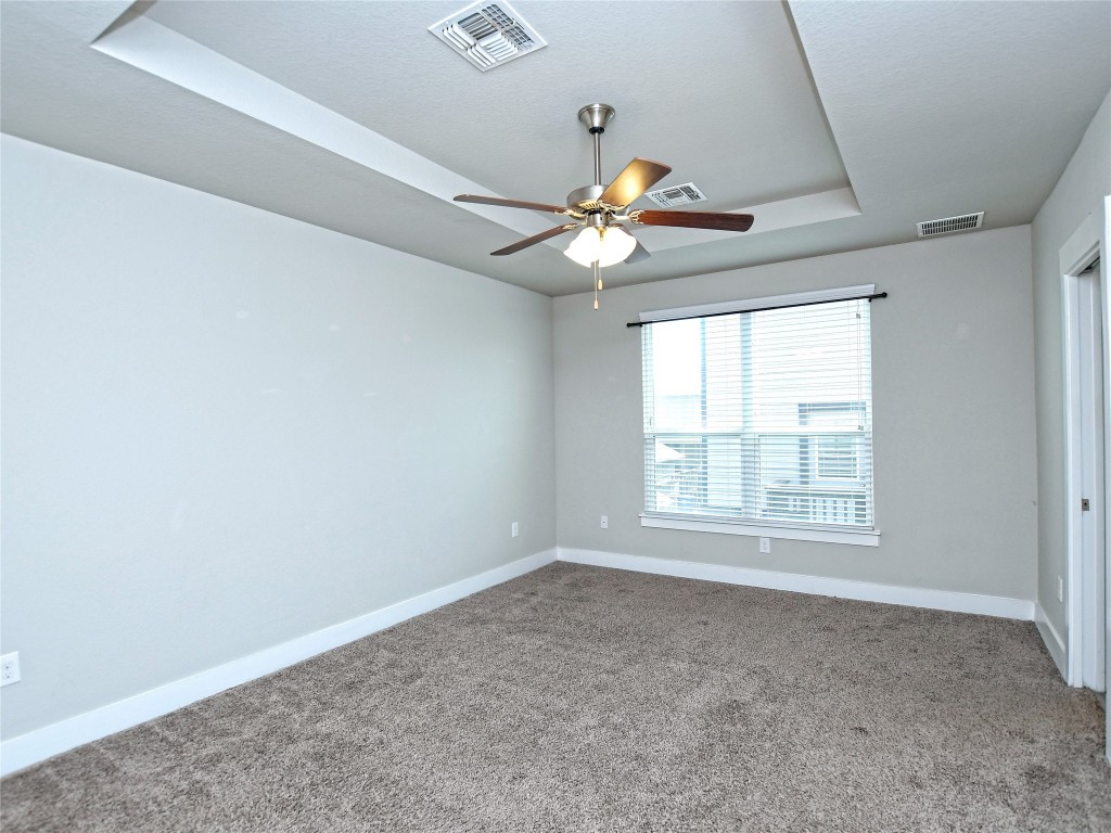 7509 Wildcat Pass Austin, TX 78757 - Photo 20 of 38 Empty room featuring a tray ceiling, carpet floors, and ceiling fan