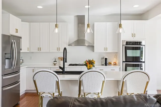 a kitchen with stainless steel appliances granite countertop a table chairs refrigerator and sink