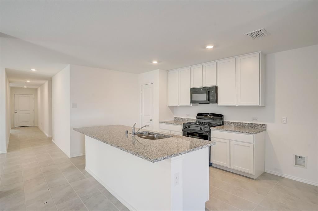 2817 Watchpoint Road Little Elm, TX 75068 - Photo 13 of 40 a kitchen with a sink a stove top oven and white kitchen