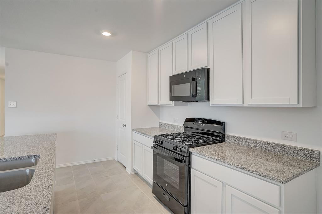 2817 Watchpoint Road Little Elm, TX 75068 - Photo 15 of 40 a kitchen with granite countertop white cabinets stainless steel appliances and a counter space