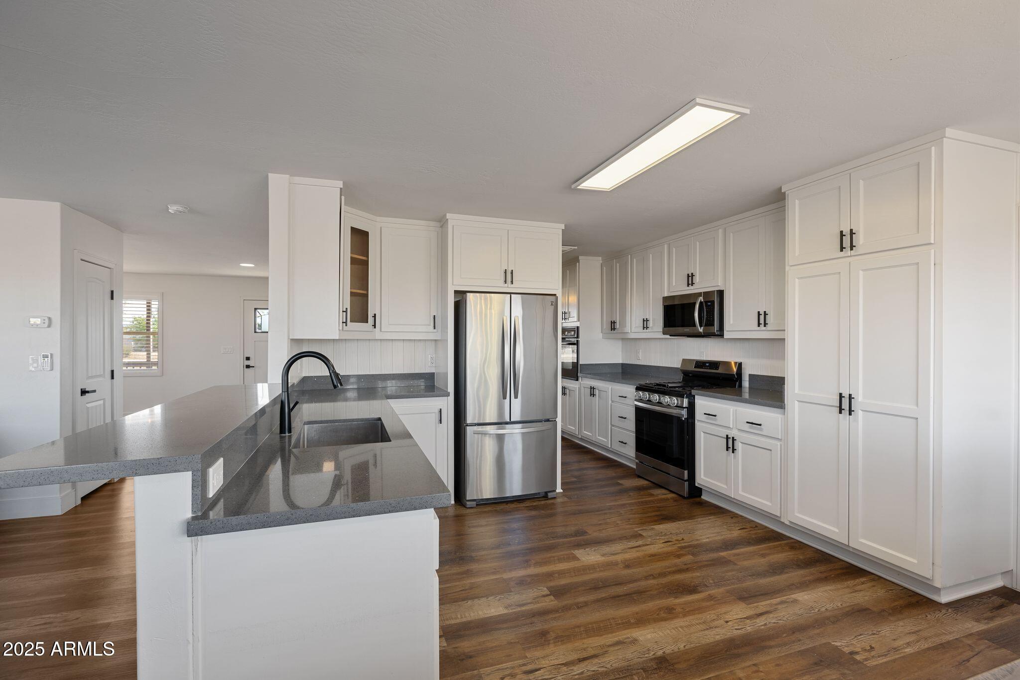 25090 North High Desert Road Paulden, AZ 86334 - Photo 18 of 54 a kitchen with a refrigerator sink and wooden cabinets