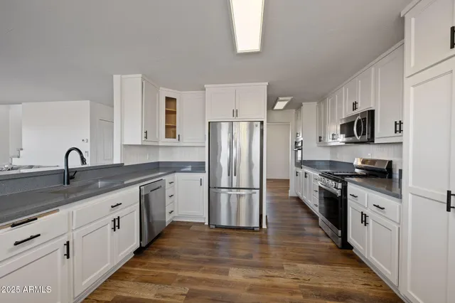 a kitchen with stainless steel appliances white cabinets and wooden floor