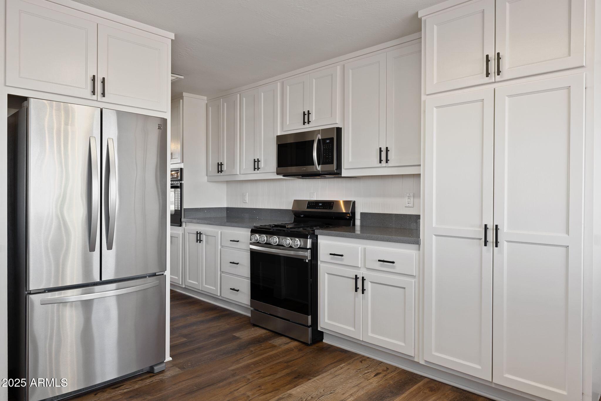 25090 North High Desert Road Paulden, AZ 86334 - Photo 20 of 54 a kitchen with stainless steel appliances white cabinets and wooden floor