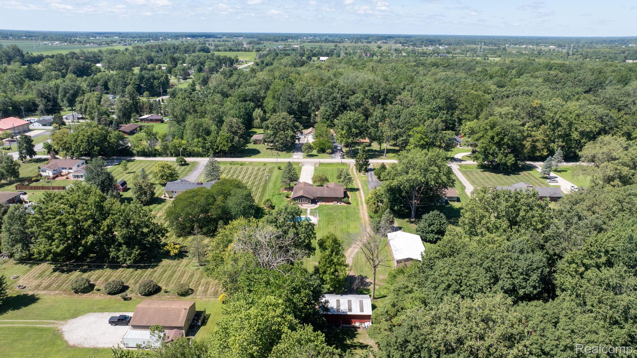 12900 Maxwell Road Carleton, MI 48117 - Photo 14 of 59 Expansive property with mature trees, a gravel driveway, and a large grassy area