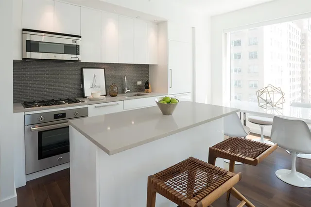 a living room with stainless steel appliances furniture and a kitchen view