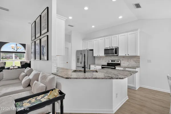 a kitchen with stainless steel appliances granite countertop a sink a stove a microwave a refrigerator and cabinets