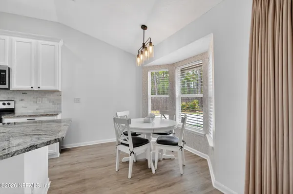 a dining room with wooden floor a chandelier a wooden table and chairs