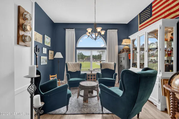 a living room with furniture a chandelier and a floor to ceiling window