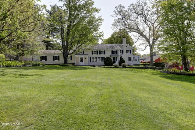 a view of a house with a big yard and large trees