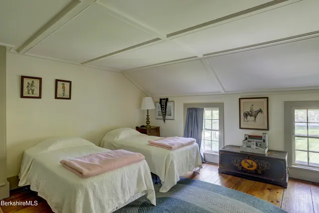 a spacious bedroom with two beds and wooden floor
