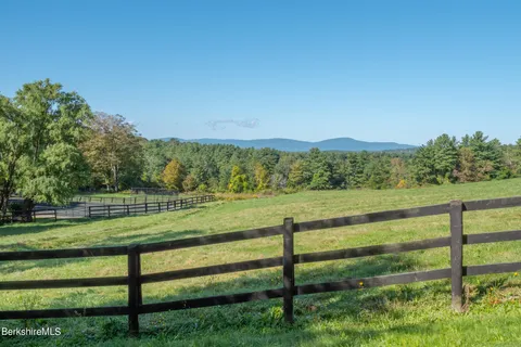 a view of a lush green outdoor space with a swimming pool and valleys in the background