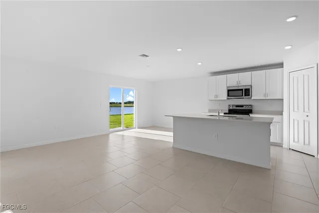 a view of kitchen with stainless steel appliances granite countertop white cabinets and window