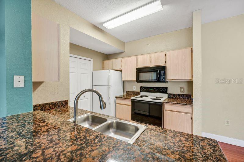 5471 Vineland Road, Unit 7301 Orlando, FL 32811 - Photo 5 of 34 a kitchen with a sink a stove and microwave