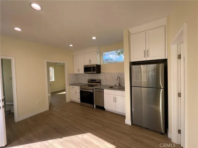 a kitchen with a refrigerator a stove top oven and wooden floor