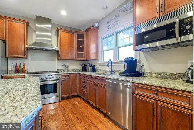 a kitchen with stainless steel appliances granite countertop a refrigerator a stove top oven a sink and dishwasher
