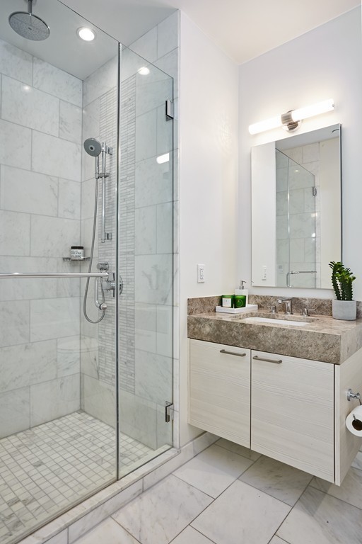 1 Franklin Street, Unit 3409 Boston, MA 02110 - Photo 14 of 18 a bathroom with a granite countertop sink a mirror and shower