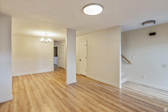 38 South 1000th Street East Payson, UT 84651 - Photo 6 of 19 Open concept living area featuring wood-finish flooring, neutral paint, a modern flush-mount ceiling light, a chandelier, and a staircase with a wood handrail