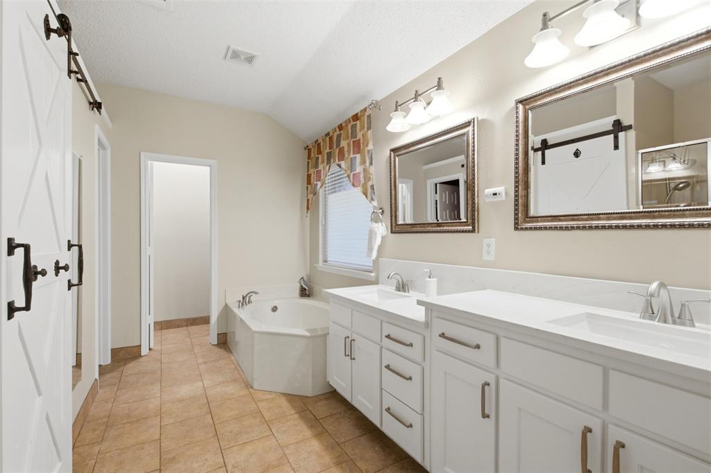 4218 Glistening Spring Rowlett, TX 75088 - Photo 20 of 39 Bathroom featuring a dual vanity with white cabinetry and countertops, framed mirrors, and an undermount soaking tub