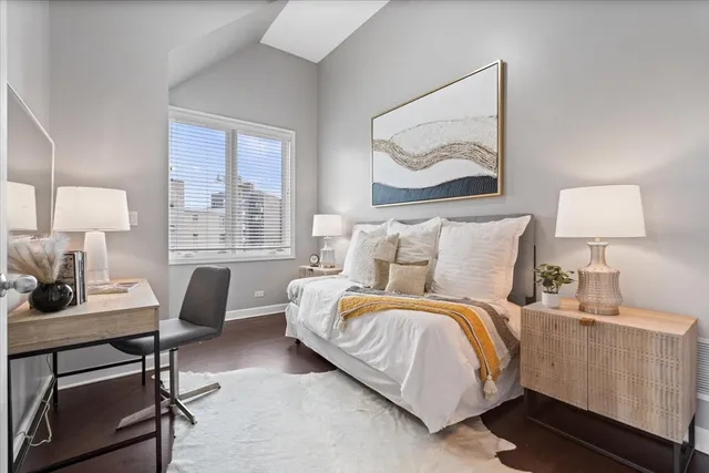 a bedroom with a bed a lamp on desk and a window