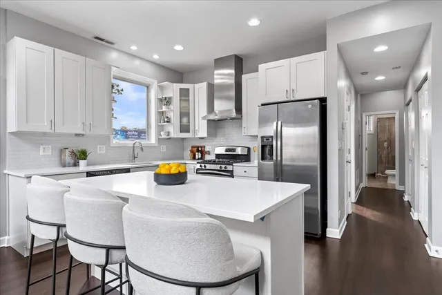 a kitchen with stainless steel appliances refrigerator and chairs
