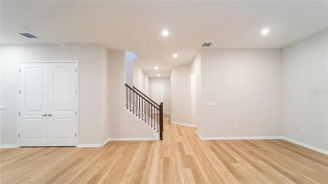 a view of an empty room with wooden floor and stairs