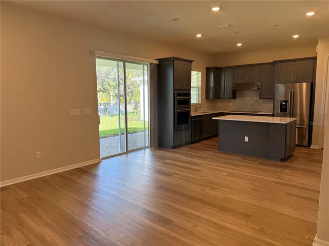 a large kitchen with wooden floor and stainless steel appliances