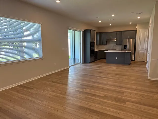 a view of kitchen with kitchen island wooden floor center island and stainless steel appliances