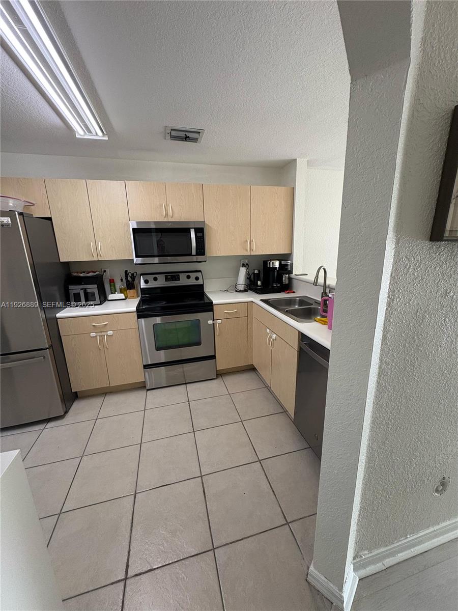 12842 Southwest 31st Street, Unit 134 Miramar, FL 33027 - Photo 8 of 30 a kitchen with a stove a sink and a refrigerator