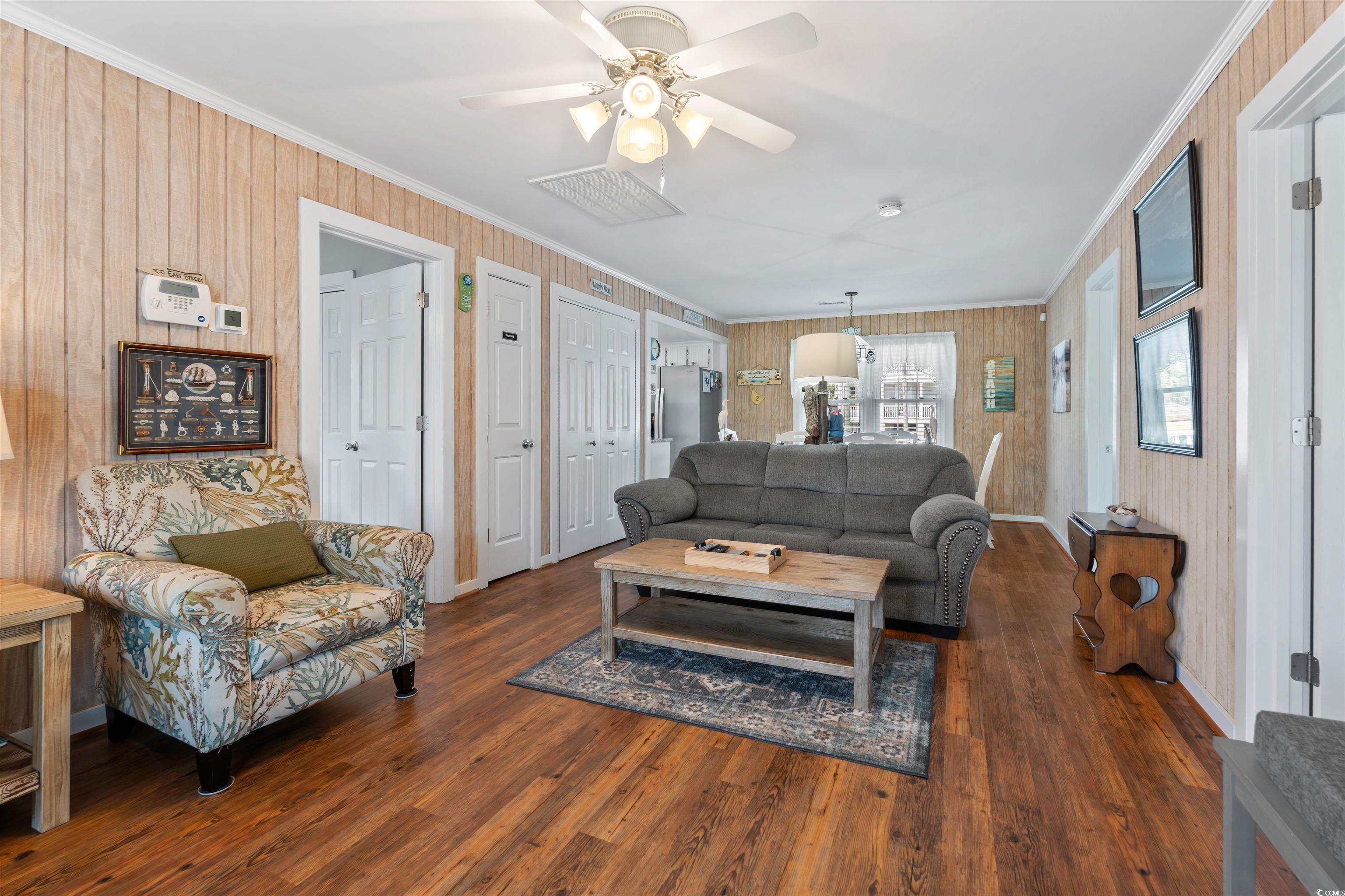 161 Easy Street Murrells Inlet, SC 29576 - Photo 16 of 40 Living room featuring crown molding, a ceiling fan, wood finished floors, baseboards, and wood walls