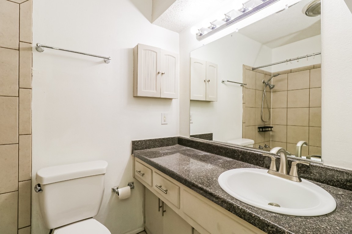 8116 Exmoor Drive, Unit B Austin, TX 78757 - Photo 14 of 15 a bathroom with a granite countertop sink a mirror and a toilet