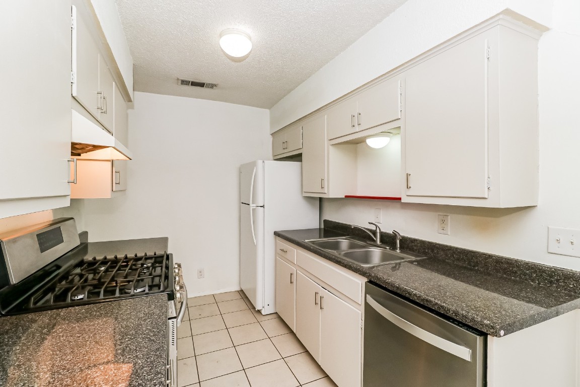 8116 Exmoor Drive, Unit B Austin, TX 78757 - Photo 7 of 15 a kitchen with granite countertop a sink a stove and cabinets
