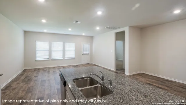 an empty room with wooden floor and a sink