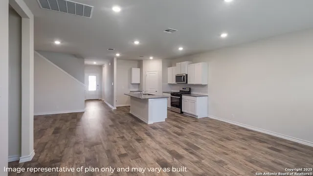 a view of kitchen with kitchen island wooden floors and stainless steel appliances