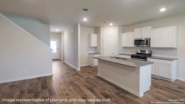 a kitchen with granite countertop a stove a sink and a refrigerator