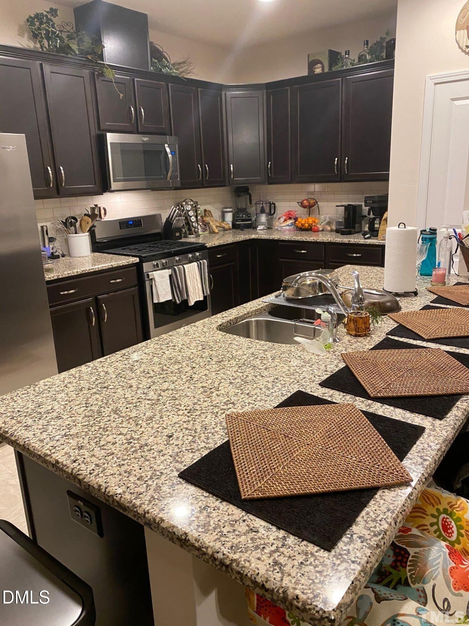 2613 Lacebark Pine Road Raleigh, NC 27616 - Photo 5 of 15 a kitchen with kitchen island granite countertop a sink a stove and a wooden cabinets