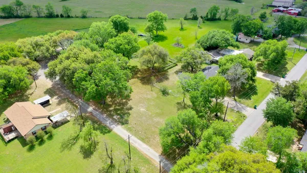 an aerial view of residential houses with outdoor space and trees all around