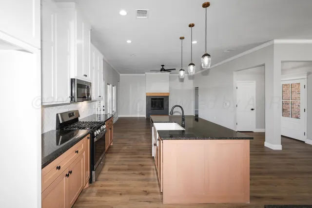 a kitchen with kitchen island granite countertop a stove a sink a refrigerator dining table and chairs