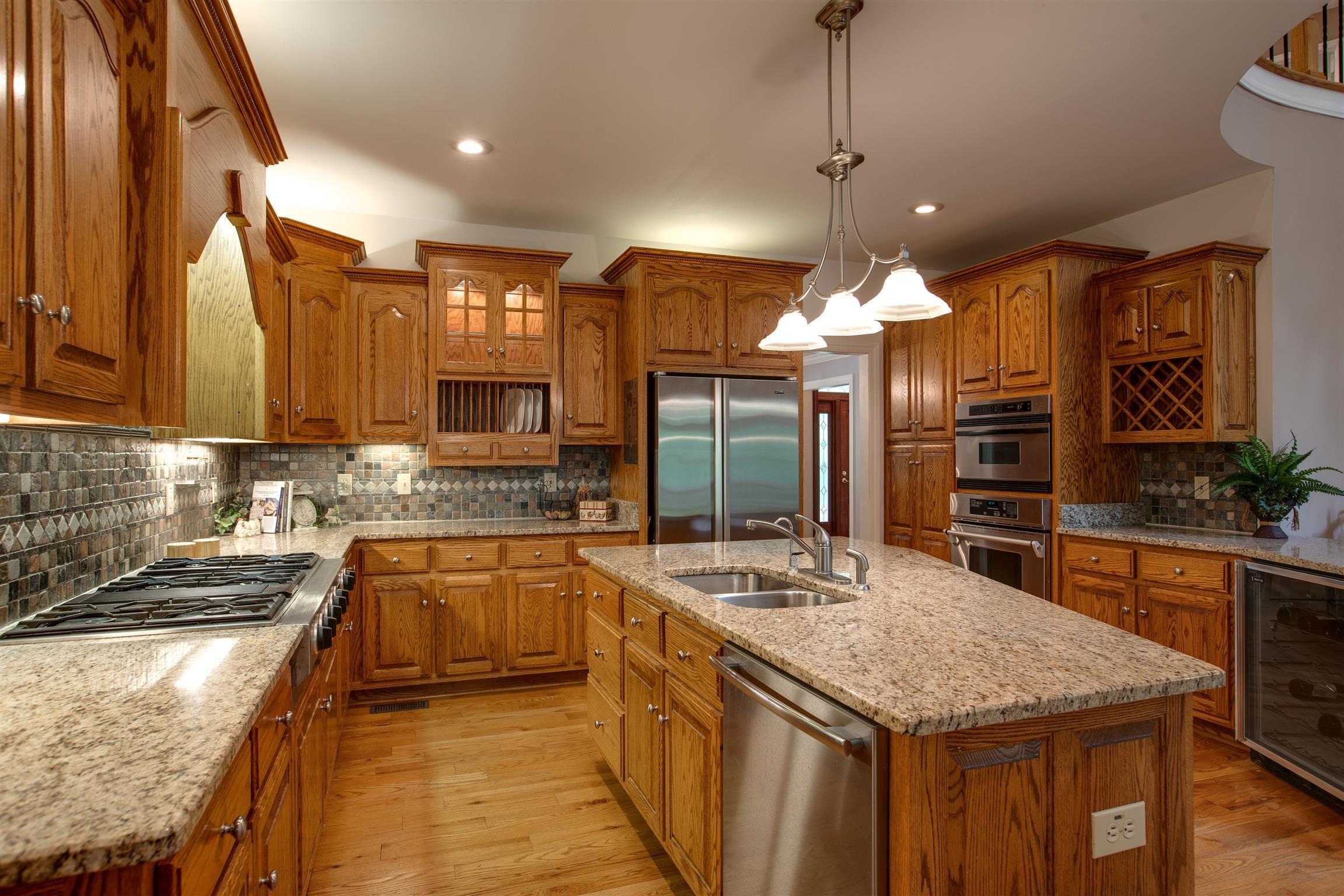 5745 Pinewood Road Franklin, TN 37064 - Photo 6 of 27 a kitchen with stainless steel appliances granite countertop wooden cabinets a sink dishwasher and a stove with wooden floor