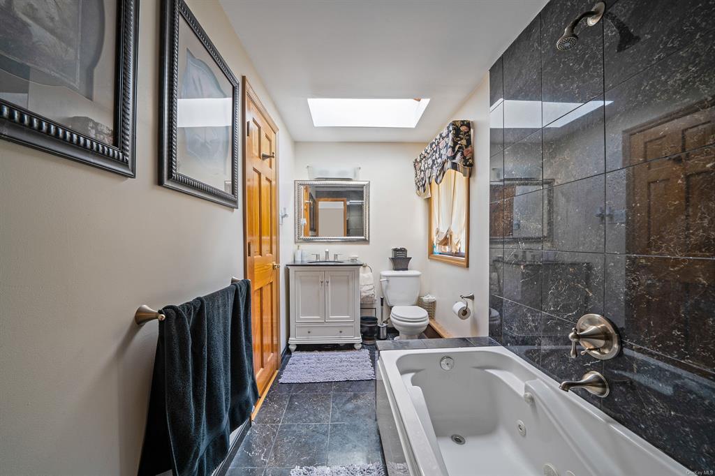 8 Brenner Road Coram, NY 11727 - Photo 25 of 43 a bathroom with a tub a sink and a large mirror