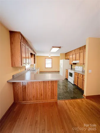 a kitchen with stainless steel appliances granite countertop a refrigerator a stove and a wooden floors