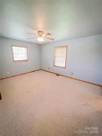 an empty room with windows and ceiling fan view