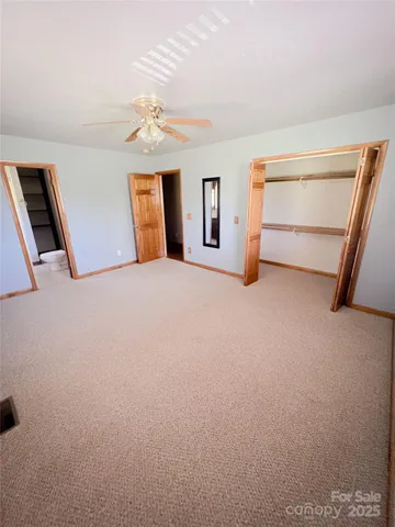 a view of an empty room with closet and windows