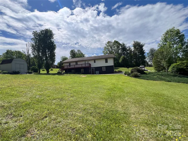 a view of a house with a big yard and large trees