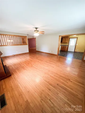 a view of an empty room with a window and wooden floor