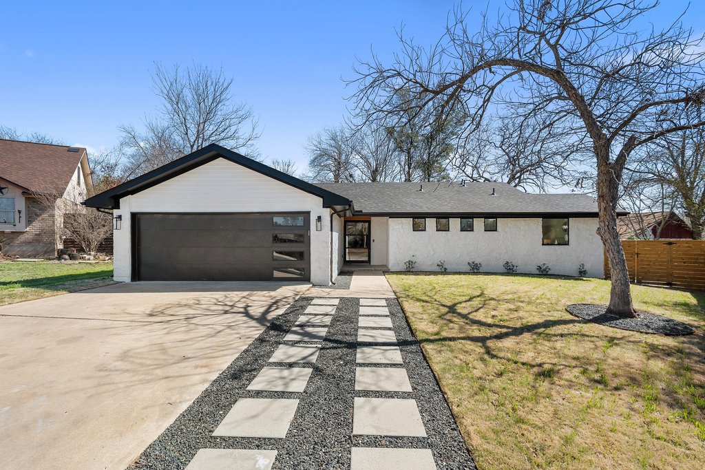 View of front of property with a front lawn, concrete driveway, and an attached garage