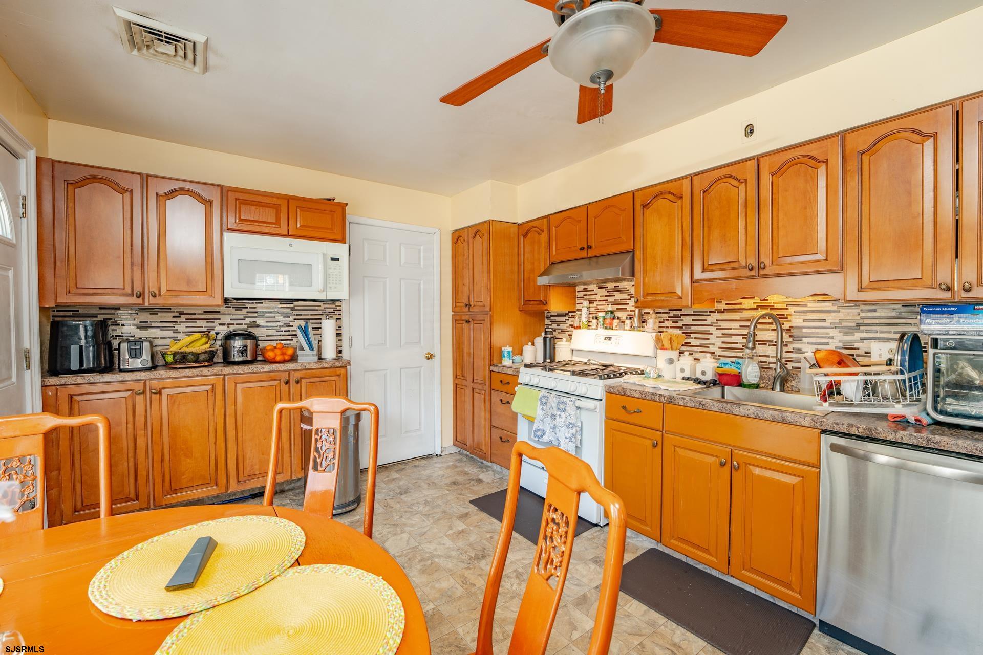 6529 Delilah Road Egg Harbor Township, NJ 08234 - Photo 16 of 70 a kitchen with stainless steel appliances granite countertop a stove a sink dishwasher and a dining table with cabinets