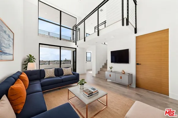 a living room with furniture a flat screen tv and a floor to ceiling window