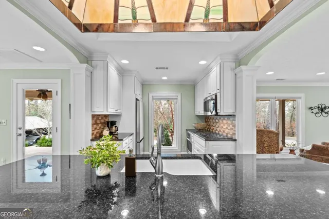 a kitchen with stainless steel appliances granite countertop a stove a refrigerator a kitchen island a table and chairs with wooden floor