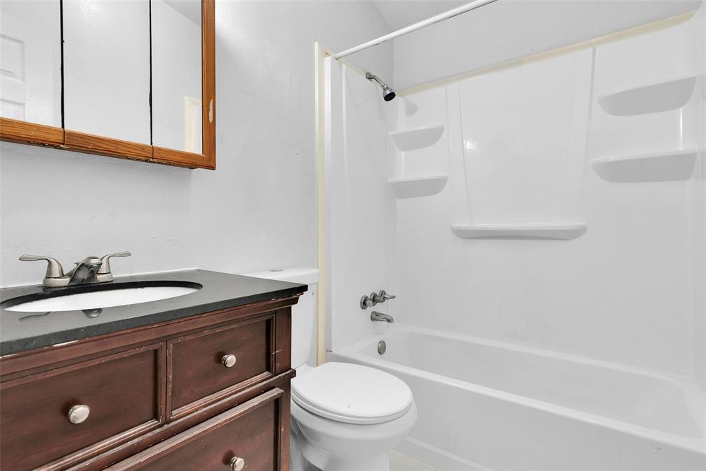 515 Forrest Lane Denison, TX 75021 - Photo 9 of 15 a bathroom with a granite countertop sink a toilet and bathtub