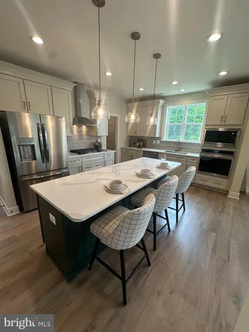 a kitchen with granite countertop a table chairs stainless steel appliances and wooden floor